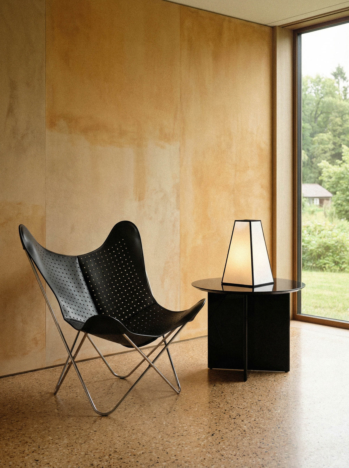 Fauteuil Papillon Cuir noir ajouré - Structure inox - Vue de 3/4 dans un intérieur moderne