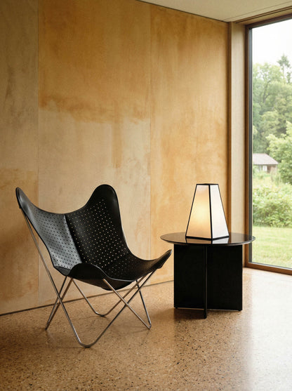 Fauteuil Papillon Cuir noir ajouré - Structure inox - Vue de 3/4 dans un intérieur moderne