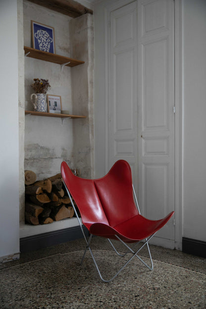 Fauteuil Papillon Cuir rouge - Structure inox - Vue de 3/4 dans un salon