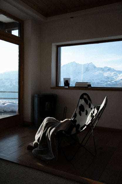 Fauteuil Papillon Cuir Vache Noire -  Structure Noire - Vue de 3/4 au milieu d'un salon à la montagne