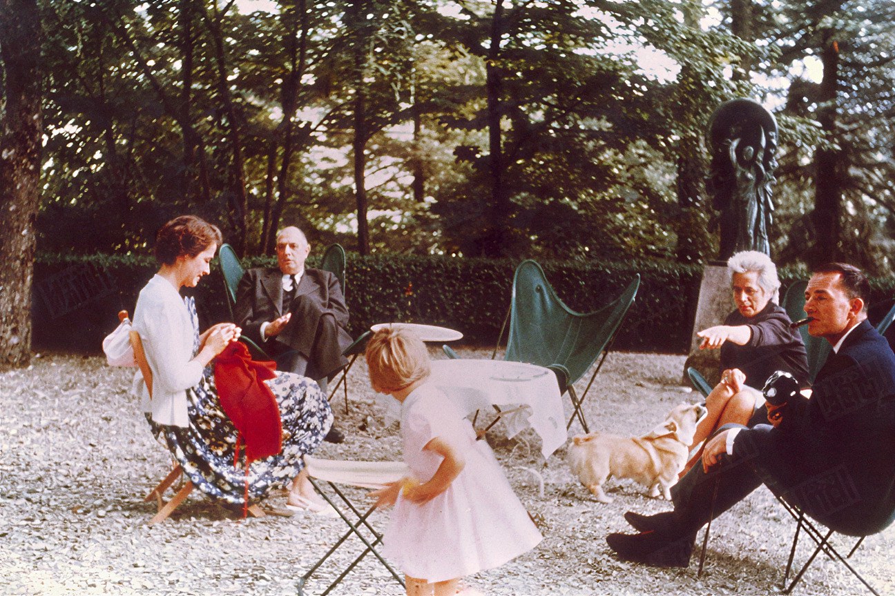 Archive familiale, fin des années 1950 : trois générations réunies dans un jardin, assises dans des fauteuils papillon à structure acier